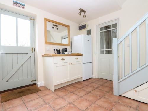 uma cozinha com armários brancos e uma porta em Oreo's Cottage em St. Agnes