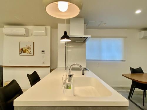 a white kitchen with a sink and a table at Villa Monica in Nagoya