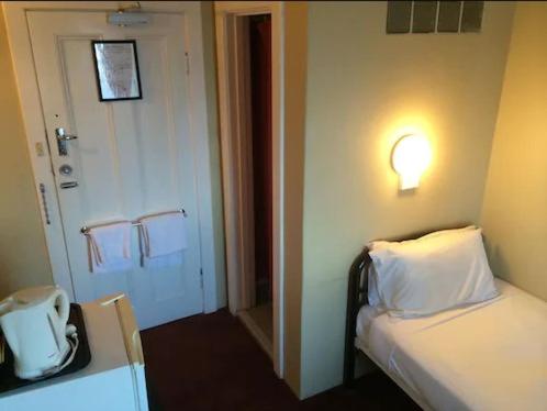 a hotel room with a bed and a light on the wall at Anchorage Seafront Hotel in Victor Harbor
