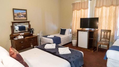 a hotel room with two beds and a flat screen tv at Anchorage Seafront Hotel in Victor Harbor