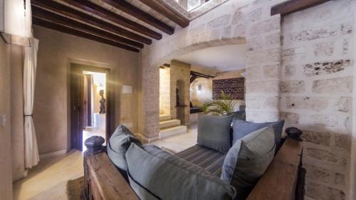 a living room with a couch and a stone wall at The Charming Lonno Lodge Watamu in Watamu