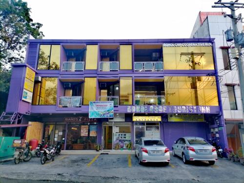un edificio púrpura con coches aparcados delante de él en Bohol Coop Tourist Inn, en Tagbilaran City