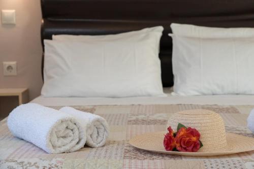 a bed with towels and a hat and flowers on it at Minas Apartments in Divarata