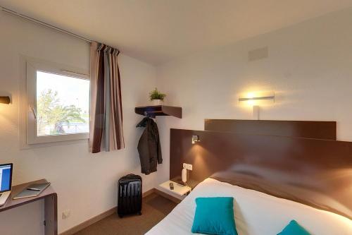 ein Hotelzimmer mit einem Bett und einem Fenster in der Unterkunft The Originals Access, Hôtel Béziers Est in Béziers