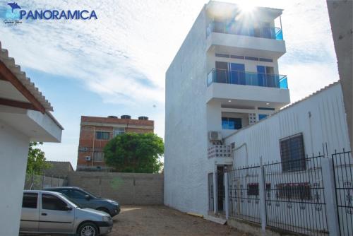 a white building with a car parked in front of it at Apartahotel Sueños Libres Necoclí in Necoclí