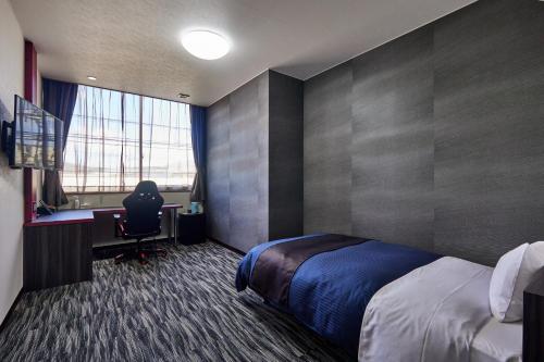 a bedroom with a bed and a desk and a window at SAIDAIJI GRAND HOTEL - Vacation STAY 67891v in Setouchi