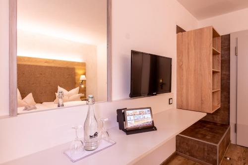 a room with a television and a counter with a bottle at Zur Post Kümmersbruck Hotel & Tiny Houses in Kümmersbruck