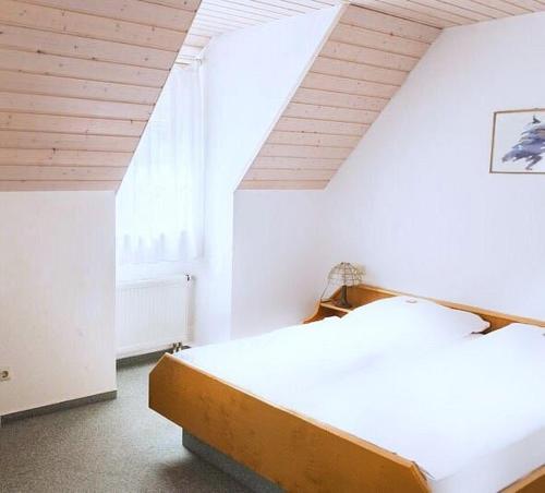 a white bedroom with a bed and a window at Engelhof in Weilheim an der Teck