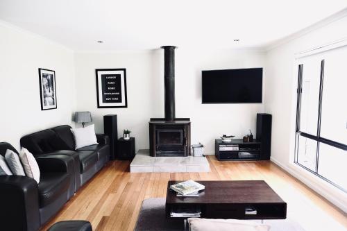 a living room with a black couch and a fireplace at Belford House in Myrtleford