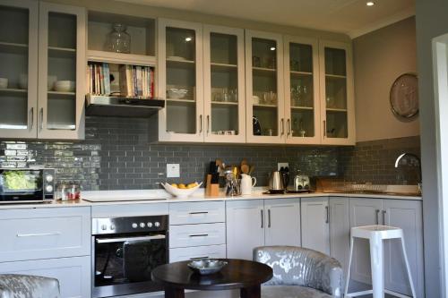 a kitchen with white cabinets and a table and chairs at The Great Gatsby Houghton in Johannesburg