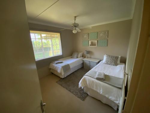 a small bedroom with two beds and a window at Under The Oak in Underberg