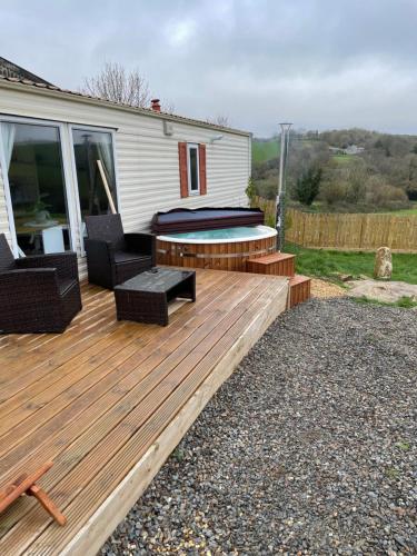 una terraza de madera con 2 sillas y una mesa en Private country caravan surrounded by fields en Liskeard