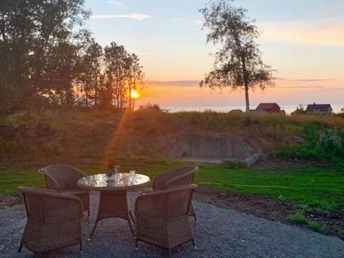a table and chairs with the sunset in the background at 9 person holiday home in Fj rtoft in Fjørtoft
