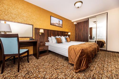 ein Hotelzimmer mit einem großen Bett und einem Schreibtisch in der Unterkunft Gradiali Wellness and SPA in Palanga