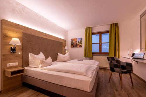 a hotel room with a large bed and a desk at Zur Post Kümmersbruck Hotel & Tiny Houses in Kümmersbruck