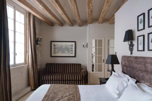 een slaapkamer met een bed en een bank bij Hotel Saint-Louis Marais in Parijs