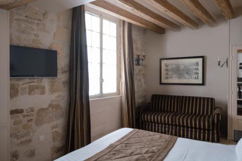 a bedroom with a bed and a chair and a television at Hotel Saint-Louis Marais in Paris