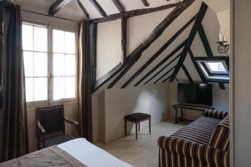 a bedroom with a bed and a couch and a desk at Hotel Saint-Louis Marais in Paris