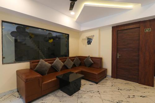 a living room with a brown couch and a large flat screen tv at FabHotel Blueark in Lucknow