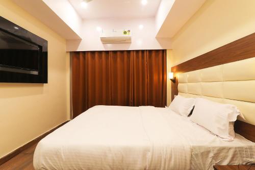 a bedroom with a white bed and a television at FabHotel Blueark in Lucknow