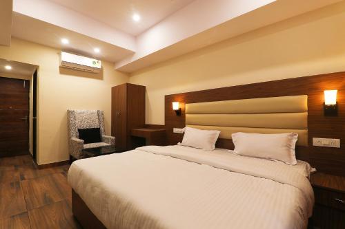 a bedroom with a large bed and a chair at FabHotel Blueark in Lucknow