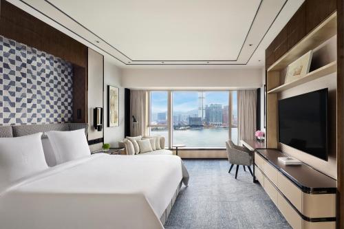 a hotel room with a large bed and a television at Four Seasons Hotel Hong Kong in Hong Kong