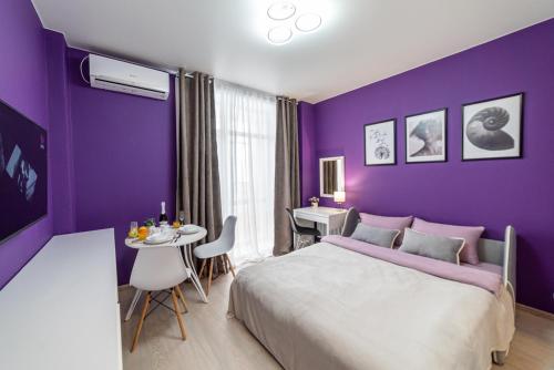 a purple bedroom with a bed and a table at "Sharm" Стильная студия на Броско in Khabarovsk