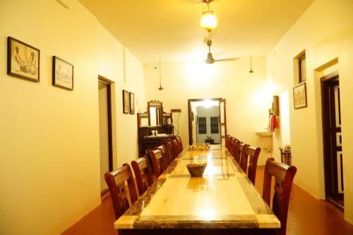 una lunga sala da pranzo con un lungo tavolo e sedie di TANJORE INN a Thanjāvūr