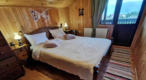 een slaapkamer met een bed met 2 kussens erop bij CABANA CU MESTECENI in Peştera
