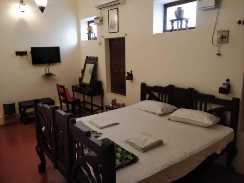a bedroom with a bed with a table and a television at TANJORE INN in Thanjāvūr