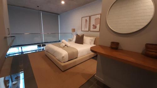 a bedroom with a white bed and a mirror at Loft -19 Umhlanga Arch New York style lofts in Durban
