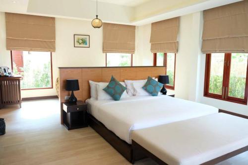 a large bedroom with two beds and windows at Triple Tree Beach Resort in Cha Am