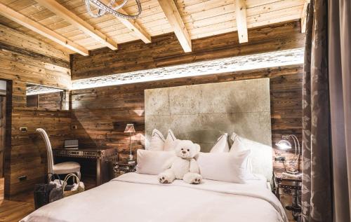 a teddy bear sitting on top of a bed at Alpin Garden Luxury Maison & SPA - Adults Only in Ortisei
