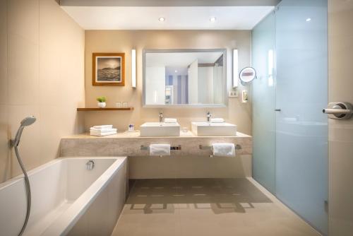 ein Badezimmer mit zwei Waschbecken, einer Badewanne und einem Spiegel in der Unterkunft Dubrovnik President Valamar Collection Hotel in Dubrovnik