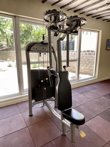 a gym with a treadmill in a room withwindows at Eleven Pearl Boutique Hotel & Spa in Diani Beach