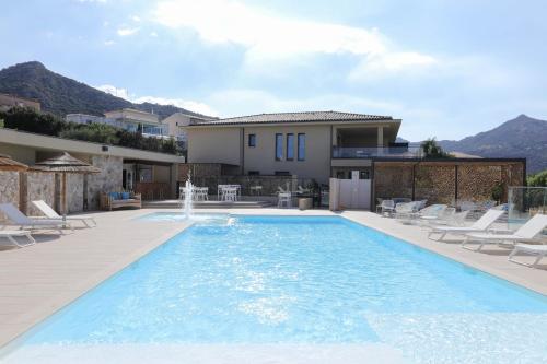 a swimming pool with chairs and a house at Résidence Storia d'Estate in LʼÎle-Rousse