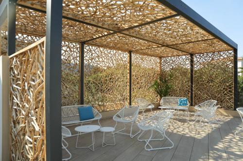 a pergola with chairs and tables on a deck at Résidence Storia d'Estate in LʼÎle-Rousse