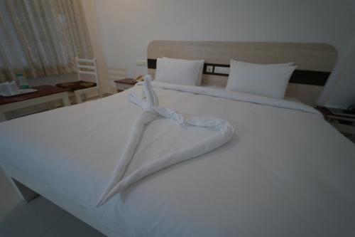 a large white bed with a towel on it at Hotel Palmyra Grand Inn in Tirunelveli