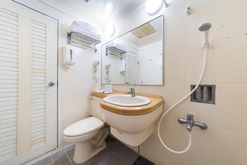 a bathroom with a toilet and a sink and a mirror at Kentington Resort in Manzhou