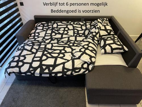 ein Bett mit einer schwarzen und weißen Decke auf einer Couch in der Unterkunft Luxe appartement I 2 slaapkamers I 2 x dubbel bed I 75m van het strand I Nieuwpoort-Bad in Nieuwpoort