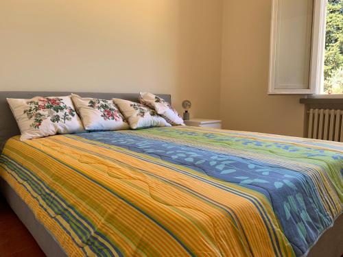 a bed with a colorful blanket and pillows on it at Spectacular Chianti View close San Gimignano in Tavarnelle in Val di Pesa