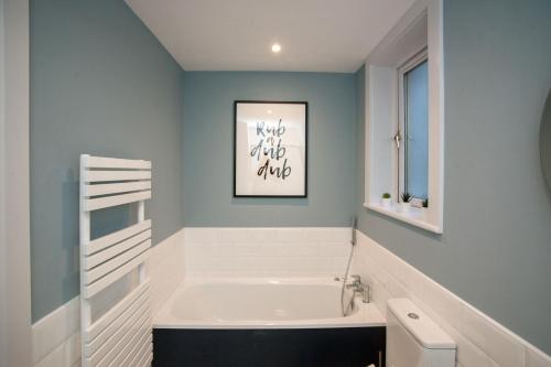 a bathroom with a white tub and a blue wall at Apartment 293 - Clifden in Clifden