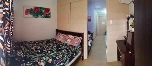 - une petite chambre avec un lit et une couverture fleurie dans l'établissement Trees Residences, à Manille