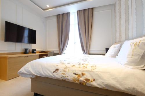 een slaapkamer met een groot bed en een televisie. bij La Maison de la Duchesse de la Vallière - Parking privé gratuit in Bergen