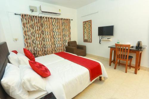 a bedroom with a bed and a desk and a television at KTDC Tamarind in Kondotti