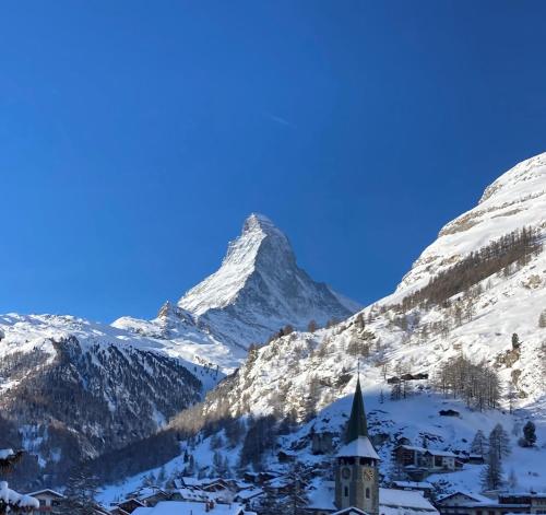 a snow covered mountain with a church in front of it at Ascot Penthouse 160 m2 Matterhorn View in Zermatt