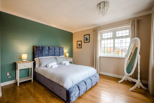 a bedroom with a bed with a blue headboard and a mirror at Platform West Hull House in Hull