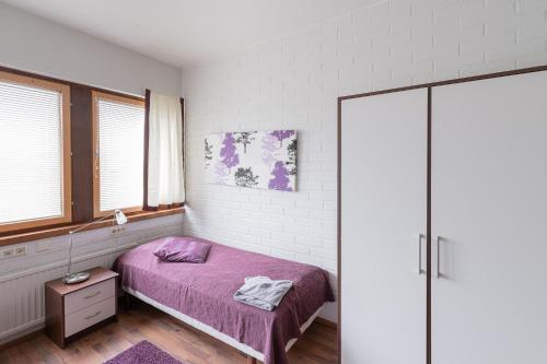 a bedroom with a bed with a purple blanket at Hotelli Selli in Vihti
