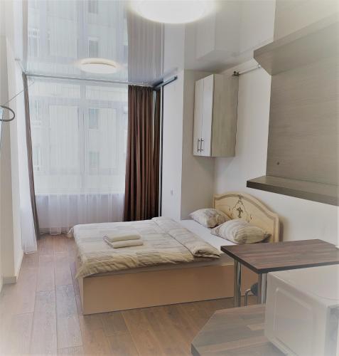 a bedroom with a bed and a table and a window at Apart Ugorska in Lviv