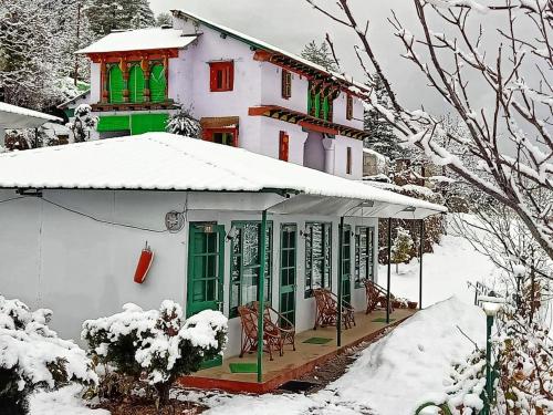 a house with green windows and snow on it at Himalayan High, Auli, By Himalayan Eco Lodges in Joshīmath